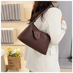 Detailed side view of a dark brown woven shoulder bag with leather flap closure
