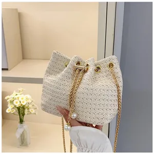 Close-up of woven bucket bag with elegant pearl drawstring and golden chain strap