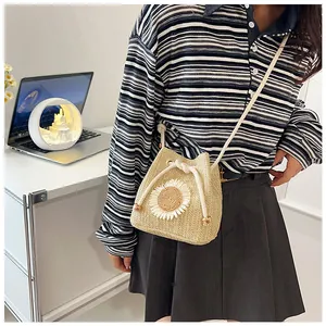 Detail view of a straw bucket bag with sunflower decor and drawstring closure on desk