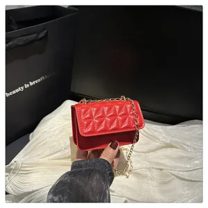 Detail of red quilted mini crossbody bag with gold chain strap and luxury leather texture