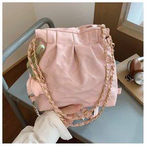 Detailed shot of pink quilted bucket bag with gold chain and floral charms