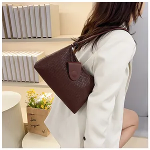 Close-up of dark brown woven shoulder bag texture on a white blazer model