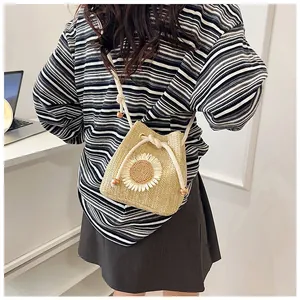Detail of straw bucket bag with sunflower embroidery and woven drawstring closure