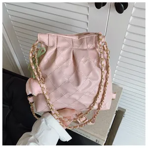Close-up of pink quilted chain bag featuring a tulip flower charm and drawstring detail
