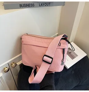 Pink nylon crossbody bag detail with adjustable strap and clover zipper pendant