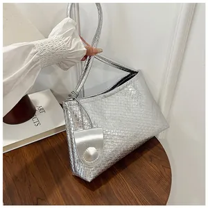 Close-up of metallic silver woven underarm bag with matching circular charm detail