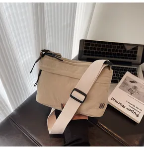 Detail of beige nylon crossbody bag with adjustable strap on a minimalist workspace