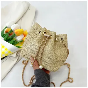 Close-up of beige woven bucket bag with pearl drawstring and golden metal chain strap