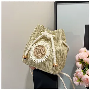 Detailed close-up of straw bucket bag featuring a white daisy and cotton drawstring