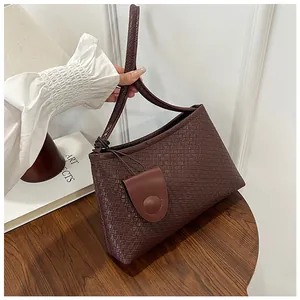 Detailed close-up of dark brown woven shoulder bag with small matching pouch attachment
