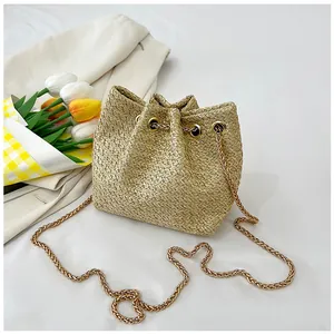 Detailed view of woven straw bucket bag with gold chain strap and drawstring closure
