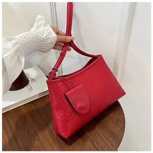 Detail of red woven texture PU leather shoulder bag on wood table with mini pouch charm