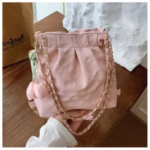 Detail of pink quilted shoulder bag with gold chain strap and tulip charm accessory