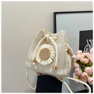 Detail of straw bucket bag featuring a white sunflower ornament and thick drawstring closure