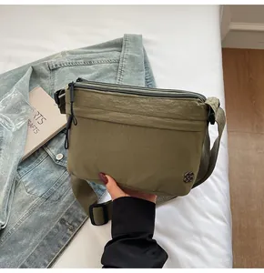Detail of army green nylon crossbody bag with dual zippers and adjustable shoulder strap