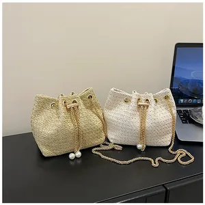 Detail of woven straw bucket bags with gold chain straps and pearl drawstring accents