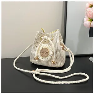 Close-up of beige woven bucket bag with daisy flower detail and cotton drawstring strap
