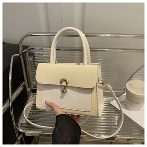 Detail of cream-colored crossbody bag with horseshoe buckle and textured fabric