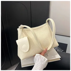 Close-up of beige woven texture underarm bag with decorative knot and small pendant bag
