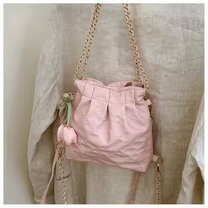 Detail of pink quilted bucket bag with golden chain and tulip flower pendant charm