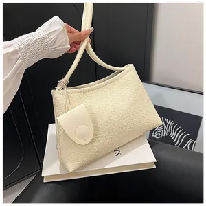 Close-up of cream woven shoulder bag texture with round handle and small charm pouch