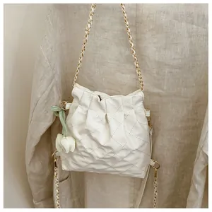 Detail of white quilted chain bag with tulip pendant and textured faux leather finish