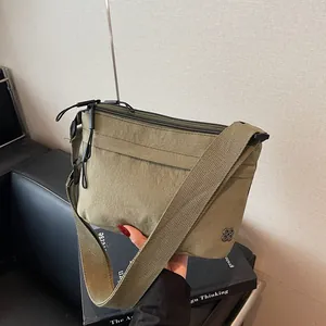 Olive green casual crossbody bag with double zippers and metallic clover logo detail