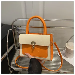 Detail of orange leather and woven fabric crossbody bag with a gold horseshoe buckle