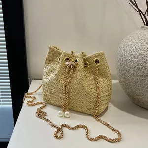Chic beige woven bucket bag with gold chain strap and pearl drawstring closure