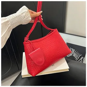 Detailed view of red woven leather tote texture with sleek matching shoulder strap