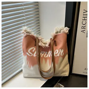 Detailed close-up of large canvas summer tote with frayed edges and pink tie-dye pattern