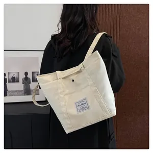 Detalle de bolso tote de lona crema con parche tejido vintage y correa ancha para el hombro
