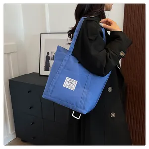 Detalle del bolso tote de nylon azul real con etiqueta de moda sobre abrigo negro largo