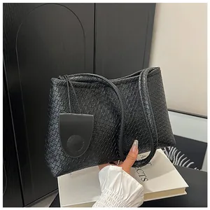 Detail of the black woven texture and minimalist handle on this stylish shoulder tote bag