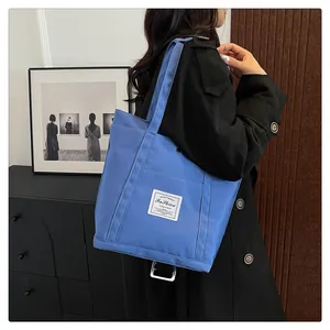 Bolso tote de moda en nylon azul con parche blanco mostrado llevado por una modelo