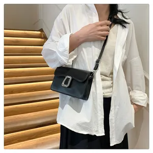 Detail of elegant black crossbody bag with silver buckle worn by a model on stairs