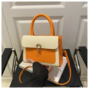 Detail showing the orange leather clasp and textured fabric on the crossbody bag