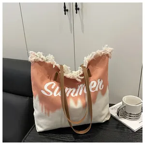 Detail of pink and white canvas tote bag with fringe edges and brown leather strap