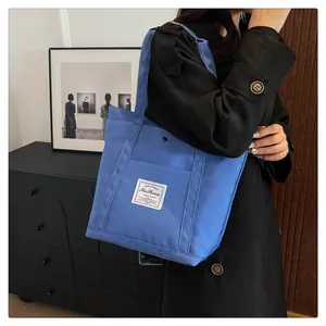 Vista de detalle del bolso tote de nailon azul real con etiqueta de moda y botón