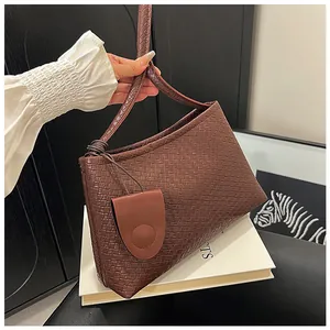Detail of dark brown woven shoulder bag featuring intricate texture and decorative pouch