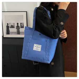 Detalle del bolso tote de nylon azul real con etiqueta de moda sobre abrigo negro