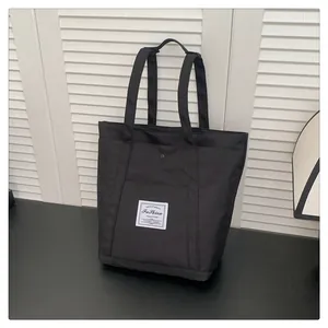 Detalle de bolso tote de nailon negro con bolsillo frontal magnético y etiqueta tejida