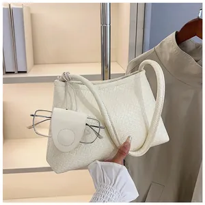 Detail of a beige woven hobo bag showing the texture and half-moon hanging accessory