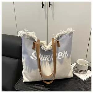 Detail of frayed edge canvas tote with Summer lettering and brown leather straps