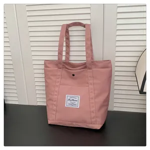 Primer plano detallado de un bolso tote de nailon rosa claro con bolsillo y etiqueta