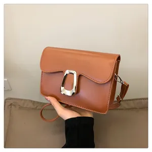 Detailed view of silver geometric metal buckle on a premium brown square leather bag