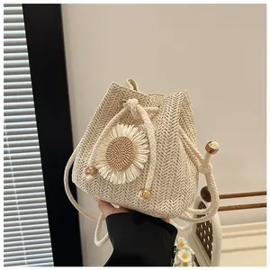 Detail of hand-woven straw bucket bag featuring a large daisy floral applique and drawstring