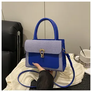 Detail of blue textured leather handbag with striped weaving and gold horseshoe buckle