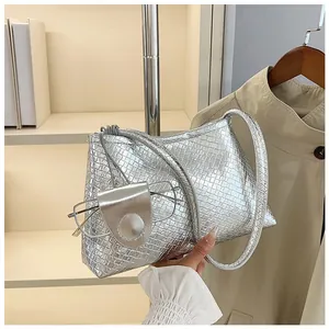 Detail of silver embossed shoulder bag with textured surface and small matching pouch