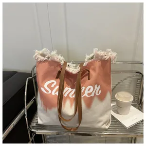 Close-up of pink and beige canvas tote with fringe trim and leather straps